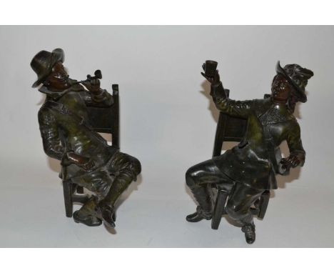 Two bronzed Spelter figures, one of a Cavalier seated and a further gentleman seated smoking a pipe, both impressed George Ma