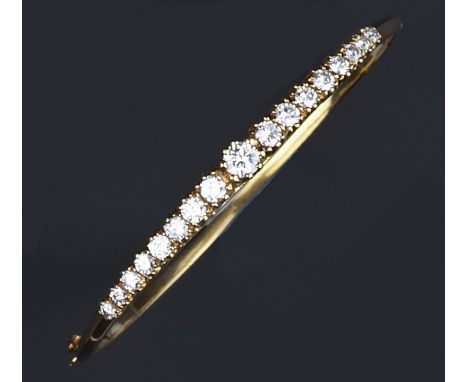 A diamond set bangle, of hinged oval form, claw set with a line of graduated brilliant-cut diamonds, 18ct gold mounted, with 