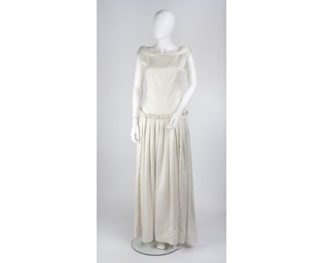 A 1940s ivory silk wedding dress, with boat-shaped collar, small cap sleeves, dropped waist with folded sash to back and plea