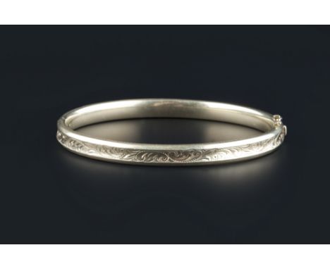 A yellow precious metal bangle, of hinged oval form, engraved with foliate scrolls and stamped '585', inner diameter 6cm