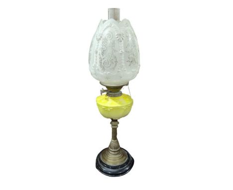 A Victorian oil lamp having moulded yellow glazed pottery reservoir, slender brass support and circular black base and with m