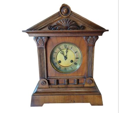 A 19th century mantel clock having circular brass dial, striking on a gong and in walnut architectural case, with key, 43cm h