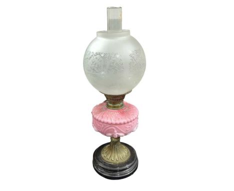 A Victorian oil lamp having moulded pink glass reservoir, brass fluted support and circular black base, with etched glass sha