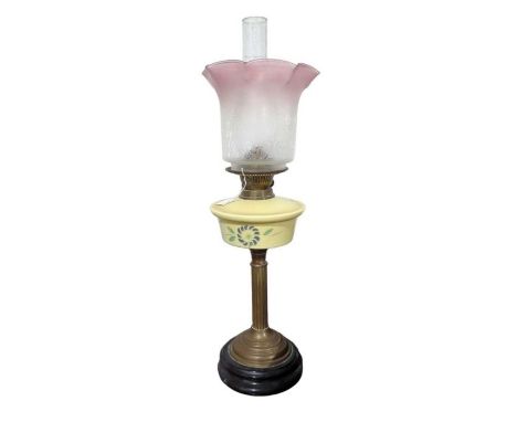 A Victorian oil lamp having painted yellow glass reservoir, brass support, circular black base and pink edged etched shade, h