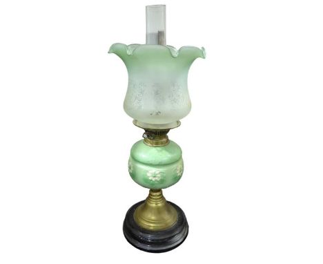 A Victorian oil lamp having green and cream glazed floral moulded pottery reservoir, brass support ad circular black base, wi