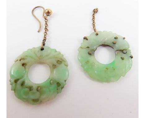 A pair of jade earrings, the round stones with carved and pierced decoration