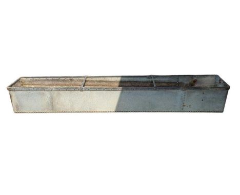 A long galvanised and rivetted drinking trough with metal rings to either end 305cm x 46.5cm