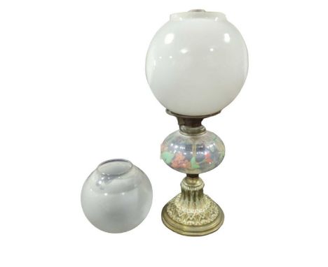 A late 19th/early 20th century oil lamp with floral painted clear glass reservoir, decorative brass base and with white glass