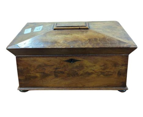 An early 19th century flame mahogany sarcophagus shaped tea caddy with two fitted compartments with hinged lids and with asso