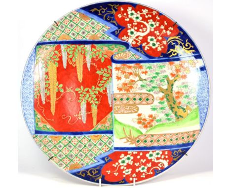 An Imari Porcelain Charger, Meiji period, typically decorated with a scroll shaped panel of flowering trees on a brocade grou