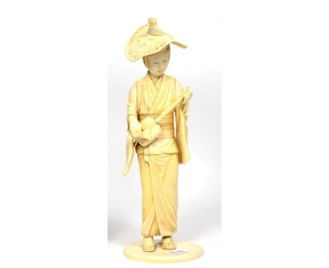 A Japanese Ivory Okimono, Meiji period, as a girl in traditional dress playing a shamisen, on an oval base, 35cm high