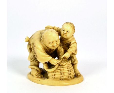 A Japanese Ivory Netsuke, Meiji period, as an eel fisherman and his son with a basket, signed Gyokumi, 5.5cm high