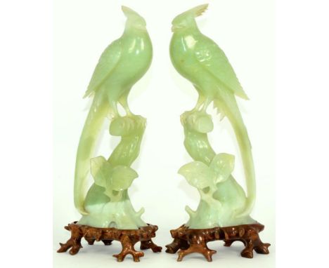 A Pair of Chinese Jade Models of Birds, each perched on a tree stump, 26cm high, on hardwood stands