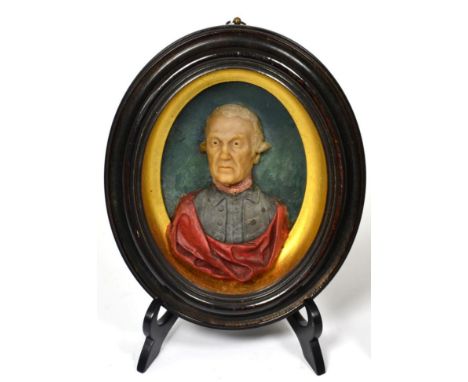 A Wax Portrait Bust of a Gentleman, circa 1770, wearing blue jacket and red cloak, in a glazed oval frame, 21cm by 19cm, the 