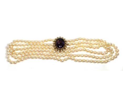 A Cultured Pearl Necklace, with an Amethyst and Pearl Clasp, three strands of uniform cultured pearls knotted to clasp with a