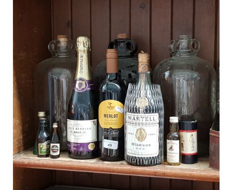 3 demijohns, various miniature alcohols, a bottle of champagne, a bottle of Martell Cognac, and a bottle of Merlot 