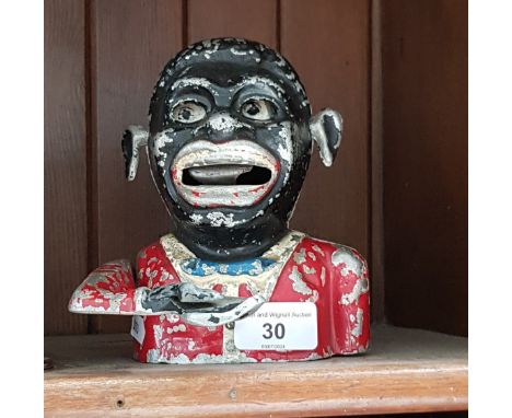 A cast metal money box.Note:- These items are listed on the basis they are illustrative of a bygone culture in which there we