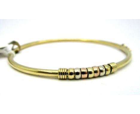 A Modern Bangle, of plain design with three colour detail to the front, hinged to snap clasp, stamped "375". 