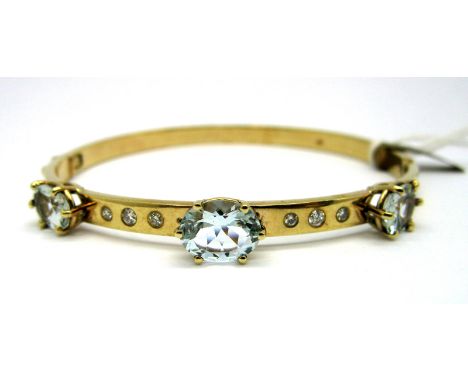 A Modern Aquamarine and Diamond Set Bangle, graduated oval claw set, with rubover set brilliant diamond spacers, hinged to sn