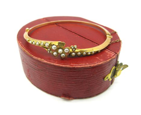 An Edwardian Pearl Set Bangle, with central flowerhead (one pearl missing) on knife edge bangle, hinged to snap clasp, in a v