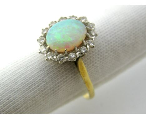 An 18ct Gold Opal and Diamond Cluster Ring, oval cabochon claw set to the centre, within border of brilliant cut stones. 