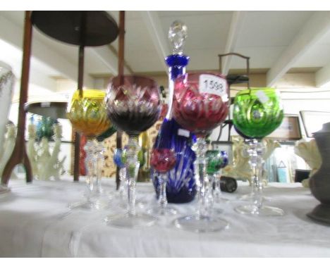 A cut glass coloured decanter and glasses.