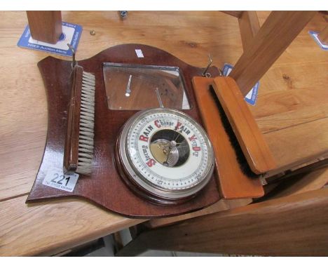 A barometer on wooden back plate with brushes.