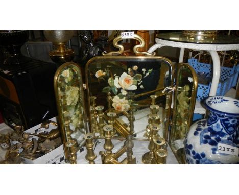 A Victorian brass triple fold fire screen with hand painted mirror panels.