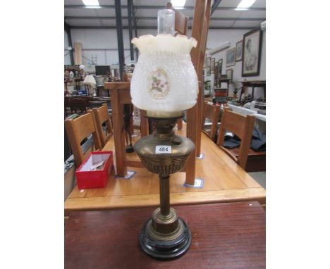 A brass oil lamp with floral shade.