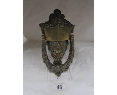 A brass mask door knocker.