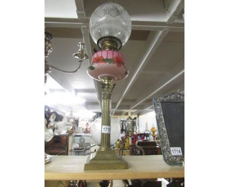 A brass Corinthian column oil lamp with floral pink font.