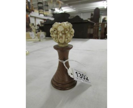 A walking stick top with Noh theatre masks.