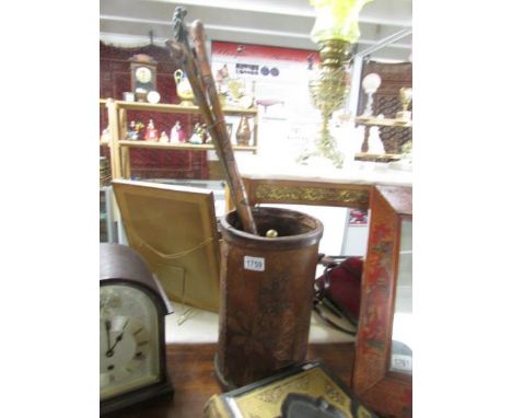 A leather stick stand and 3 walking sticks.