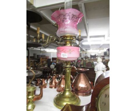 A brass oil lamp with pink glass font and cranberry etched glass shade.