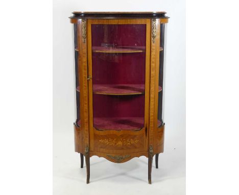 A late 19th century French walnut and marquetry inlaid vitrine, of shaped oval form, the glazed door opening to reveal three 