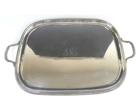 An impressive George V silver twin handled serving tray, of shaped rectangular form with a gadrooned rim and conforming appli