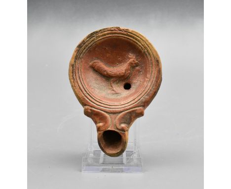 Ca. 100 – 300 AD. Ancient moulded clay oil lamp with circular panel depicting a rooster. The oil lamp is from the famous Germ