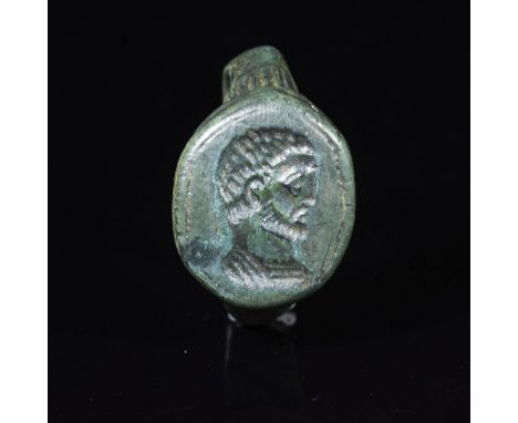 CA. 4th century AD. Rare Late Roman bronze ring with oval hoop; forming thick round bezel with carved imperial portrait; most