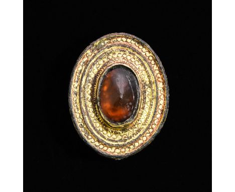 CA. 500 AD. Interesting shield-shaped fibula with elaborately decorated edge; central panel inserted with a large amber gem. 