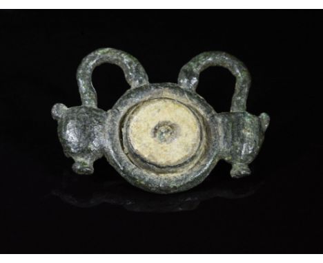 CA. 300 AD. Ancient cast bronze brooch composed of a central, enameled umbo-shaped section; terminals decorated as stylized s