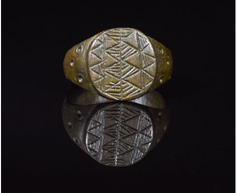 CA. 200 AD. Ancient cast bronze ring with oval hoop; applied round bezel with elaborate geometric decoration. Expertly cleane