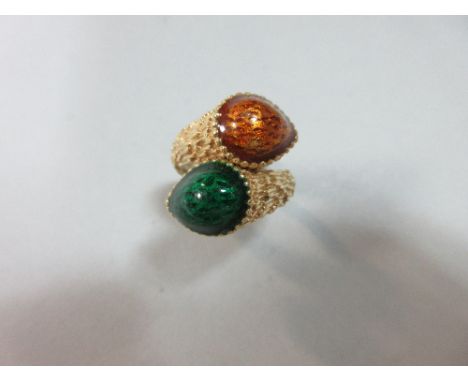 A modern crossover ring with green and orange enamel decoration, the reeded shank flaring in the front to textured crossover 