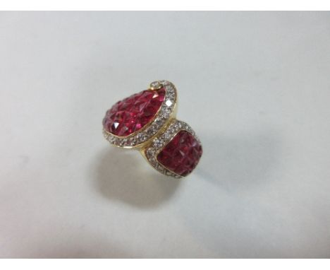An asymmetrical mystery set ruby and diamond ring, with two large flared and convex areas of approximately square rubies, eac