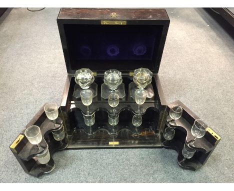 A 19th century Coromandel decanter box, marked 'Chapman's Patent', containing three stoppered decanters with pouring lips (on
