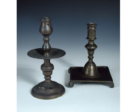 Two 17th/18th century brass candlesticks, the turned column of the English stick on a dished square base with four 'paw' feet