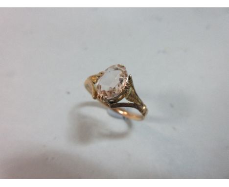 A 19th century topaz ring, the oval cut pale pinkish topaz triple claw set to a pierced trellis gallery and trifurcated folia