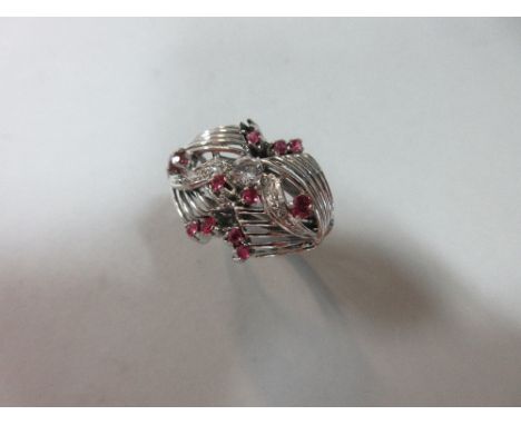 A ruby and diamond dress ring, designed as a series of curving wirework flares, set to the centre with a round cut white hard