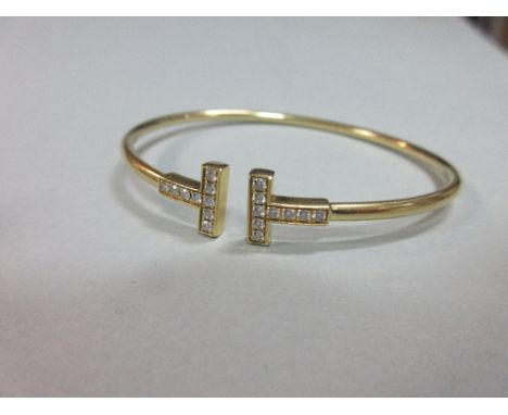 A Tiffany T diamond set bangle in original case, the tubular bangle with opposing T terminations which are delineated by line