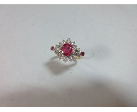 A treated ruby and diamond ring, the central cluster with an oval cut ruby in a border of diamonds with round brilliant cuts 