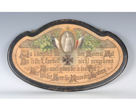 A First World War period German shaped and carved wood memorial plaque with oval aperture containing a photograph, above an a